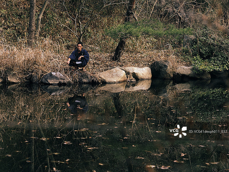 蹲在池塘边的武士图片素材