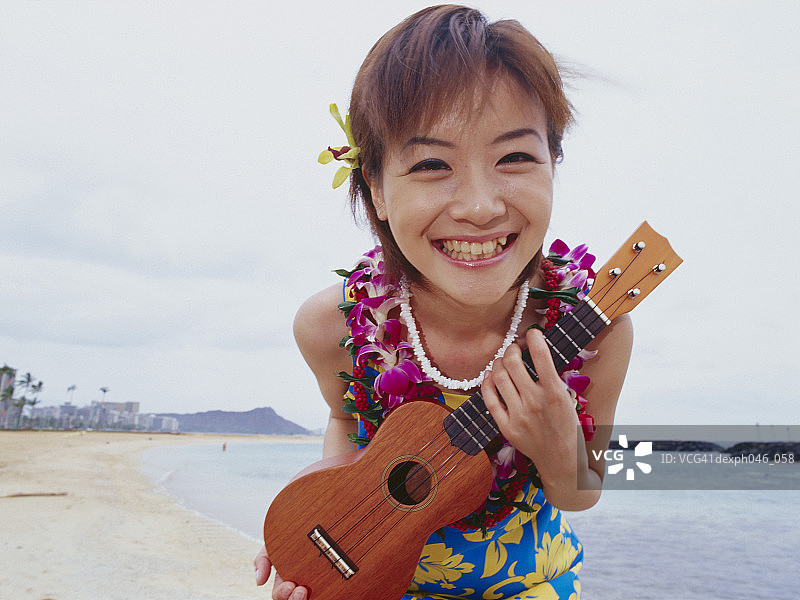 穿夏威夷衬衫 holding 尤克里里的年轻女子图片素材
