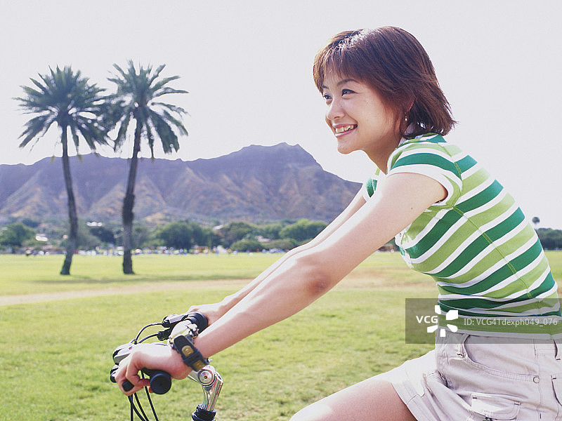 骑自行车在公园里的年轻女人图片素材