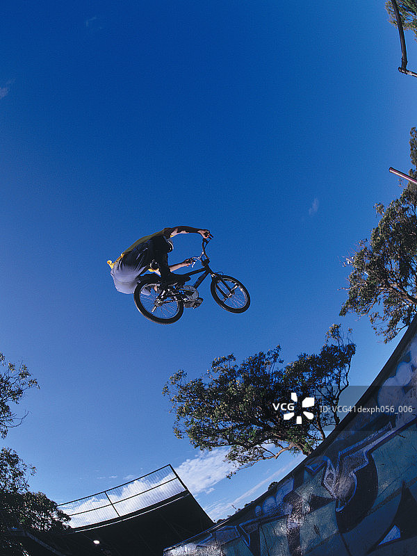 年轻男人在坡道上表演自行车特技，半空中图片素材