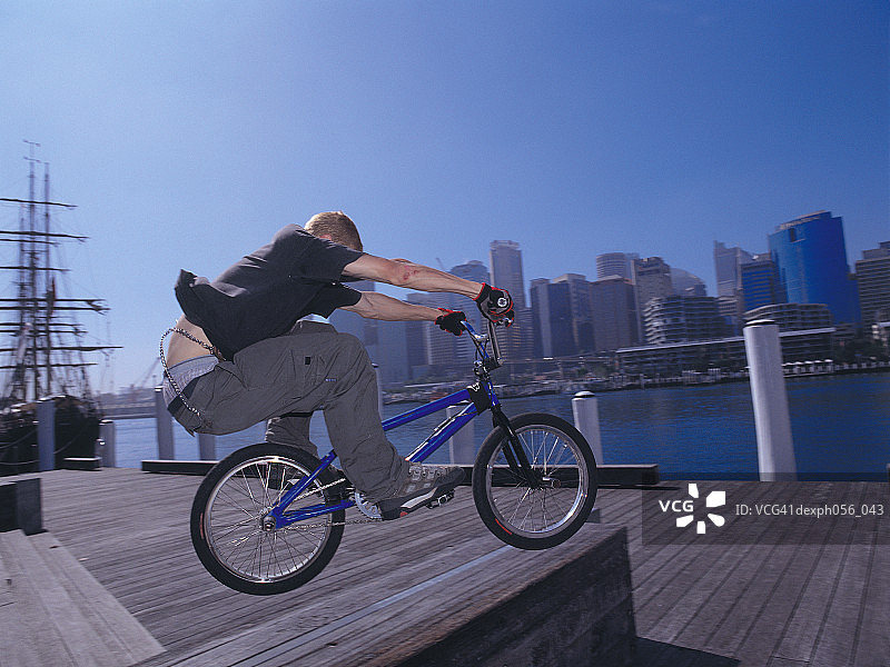 年轻男人在码头上表演自行车特技图片素材