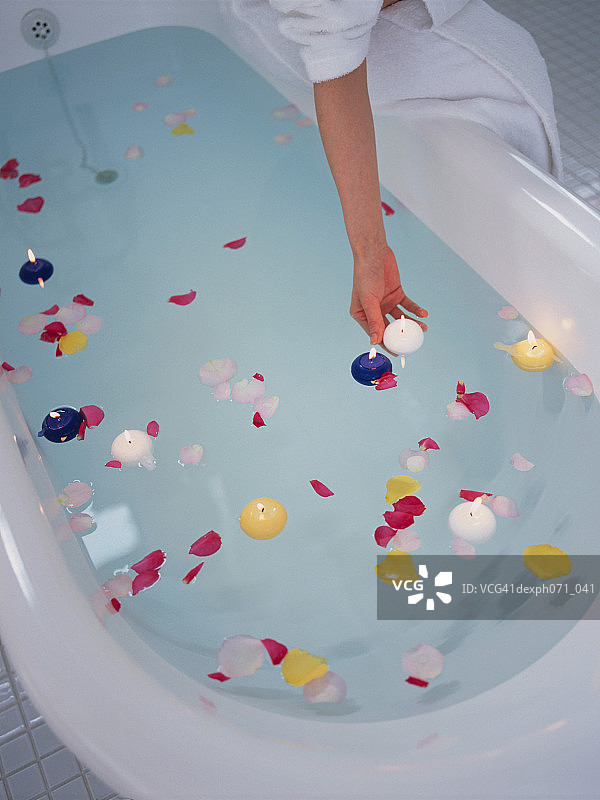 女人在浴缸里放入蜡烛和花瓣图片素材