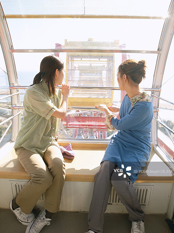 摩天轮上两名年轻女子回头的肖像图片素材