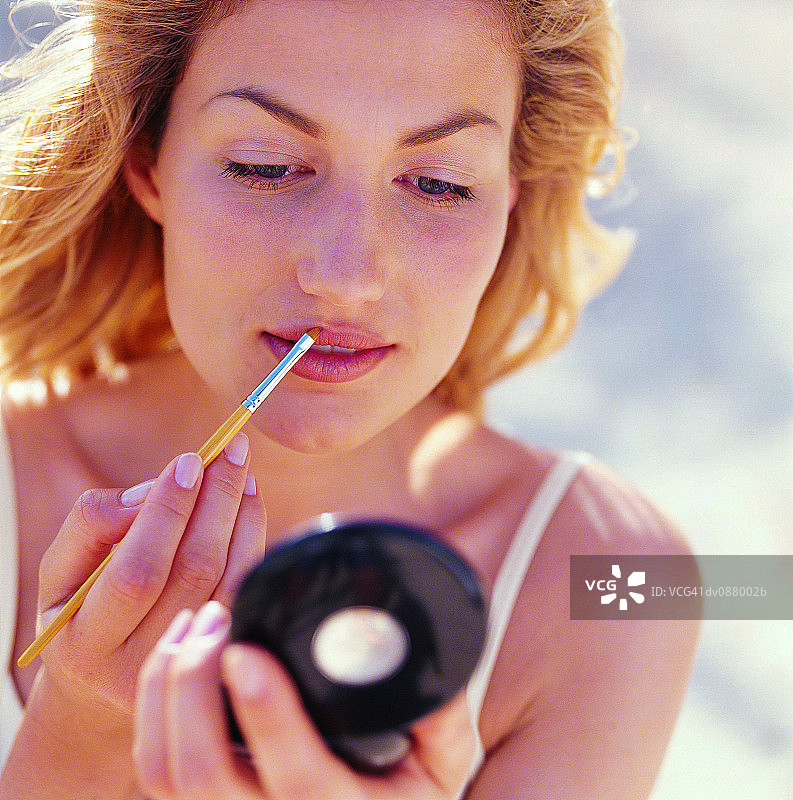 用唇刷涂口红的女人图片素材
