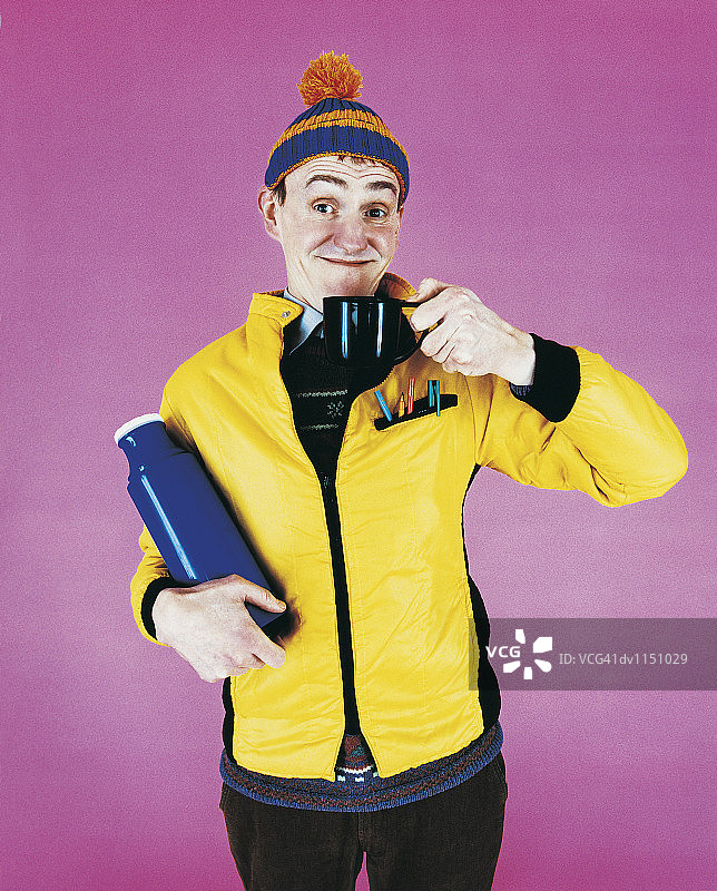 戴着绒球帽、拿着热水瓶和茶杯的火车迷肖像图片素材