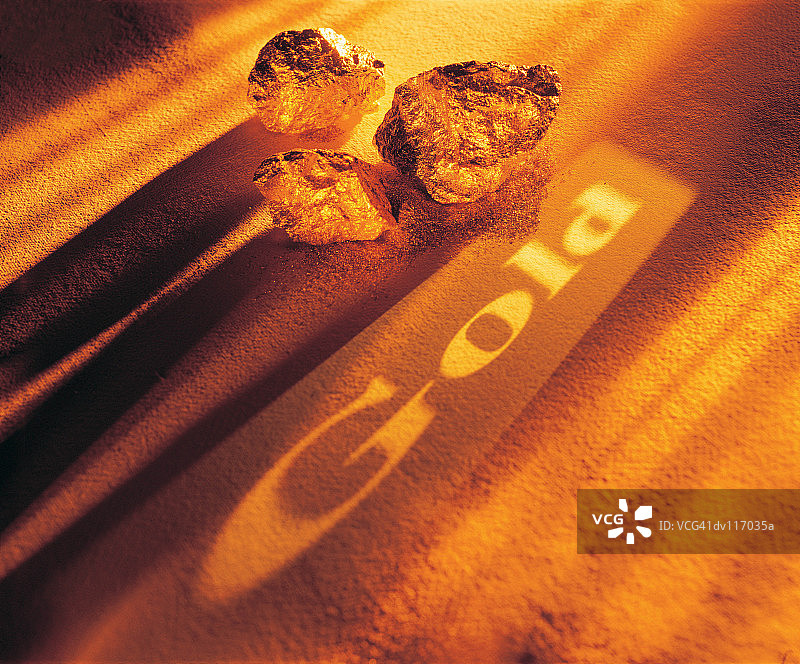 金块和投射在金粉上的文字“Gold”图片素材