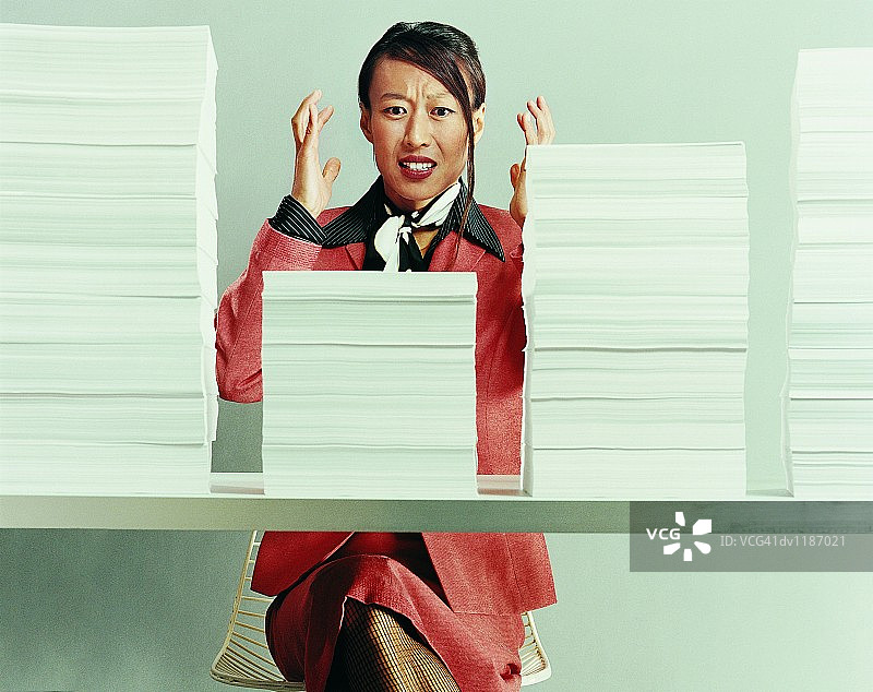 坐在办公桌后，桌上堆满文件的职业女性图片素材