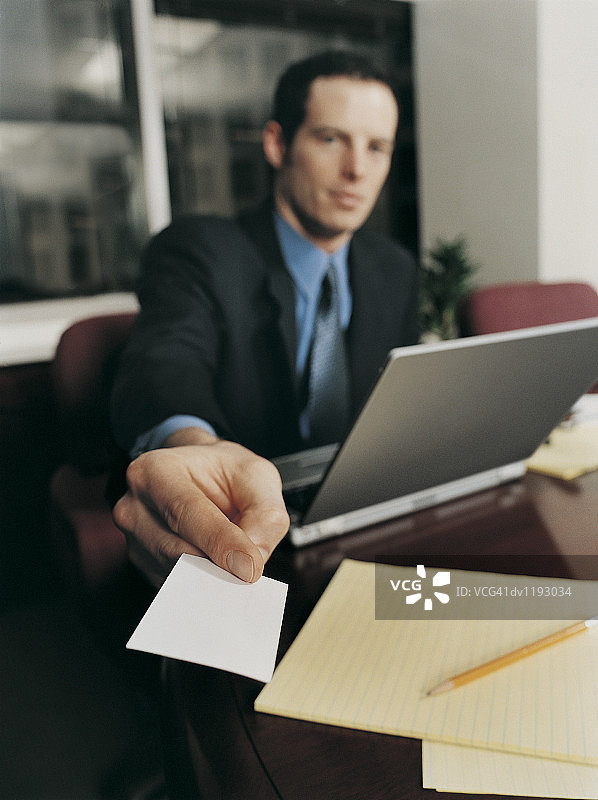 商人递名片特写，坐在桌旁使用笔记本电脑图片素材