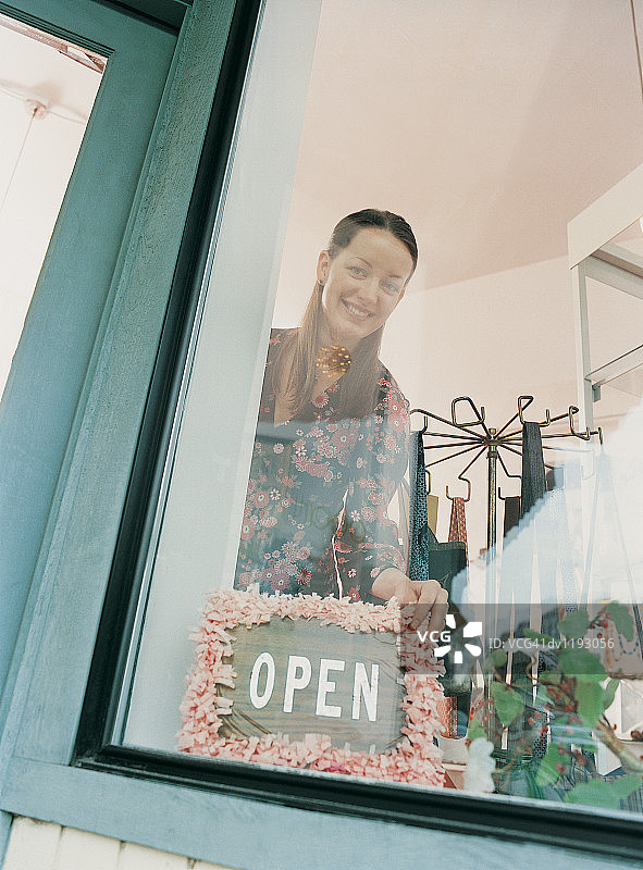 店员站在商店橱窗的开业标志旁的肖像图片素材