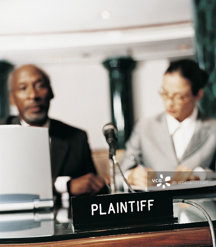 法院里，原告铭牌前，一男一女并排坐在桌旁图片素材