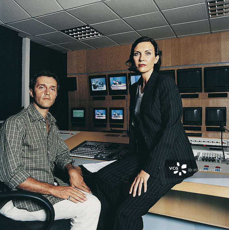 电视节目主持人和制片人坐在电视演播室的控制室里图片素材