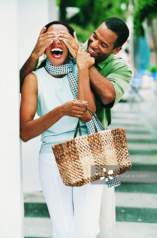 街上行走的情侣，男子用手遮住女子的脸图片素材