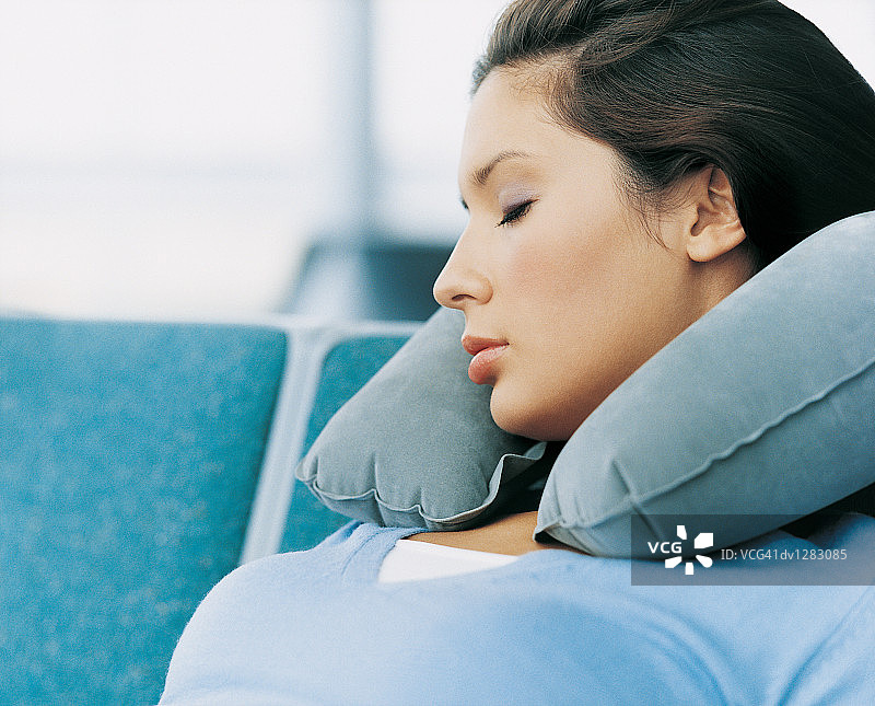 年轻女人在机场休息室使用颈枕睡觉图片素材