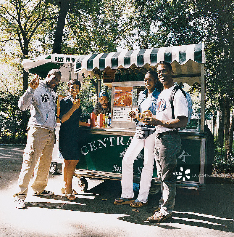 在纽约中央公园热狗摊前拿着食物的游客肖像图片素材