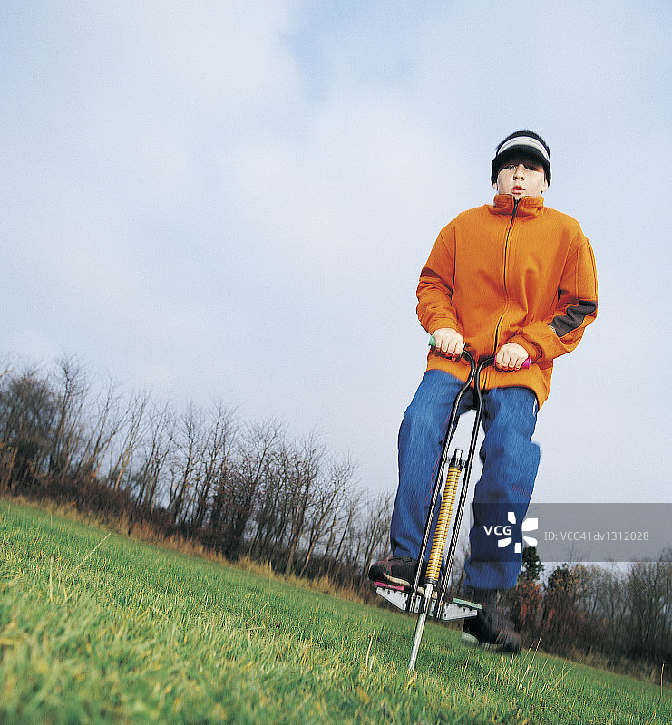 秋日公园里玩弹跳杆的男孩肖像图片素材