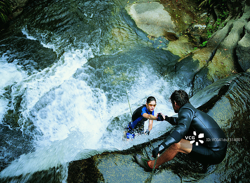 男人拉着女人爬上瀑布图片素材