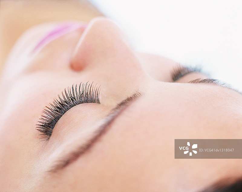 闭着眼睛涂睫毛膏的年轻女人特写图片素材