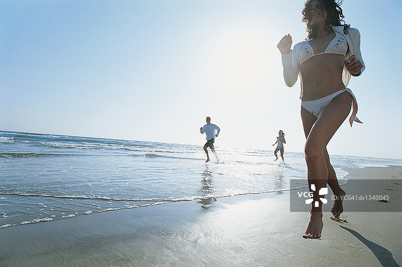 三个年轻人在海滩上奔跑的仰视角度照片图片素材