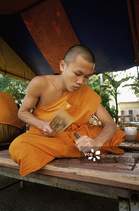 在老挝万象湄公河流域雕刻木头的佛教僧侣图片素材
