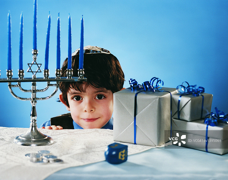 男孩在摆满传统犹太物品的桌子上探头图片素材