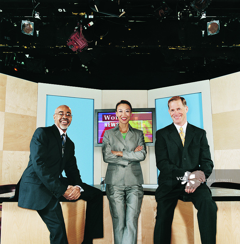 在电视演播室的桌子上就座的电视新闻主播图片素材