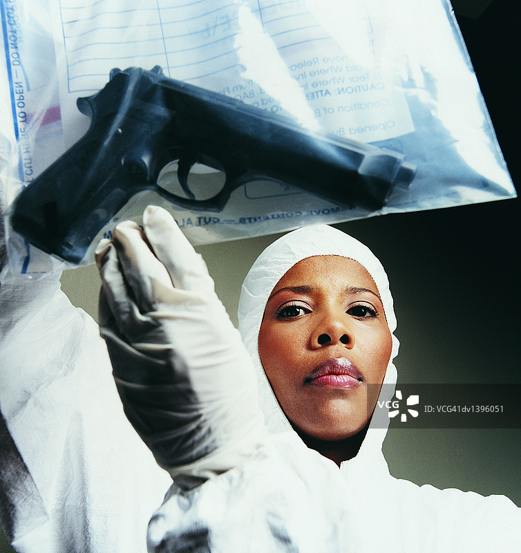 特工手持装有手枪的物证袋的低角度视图图片素材