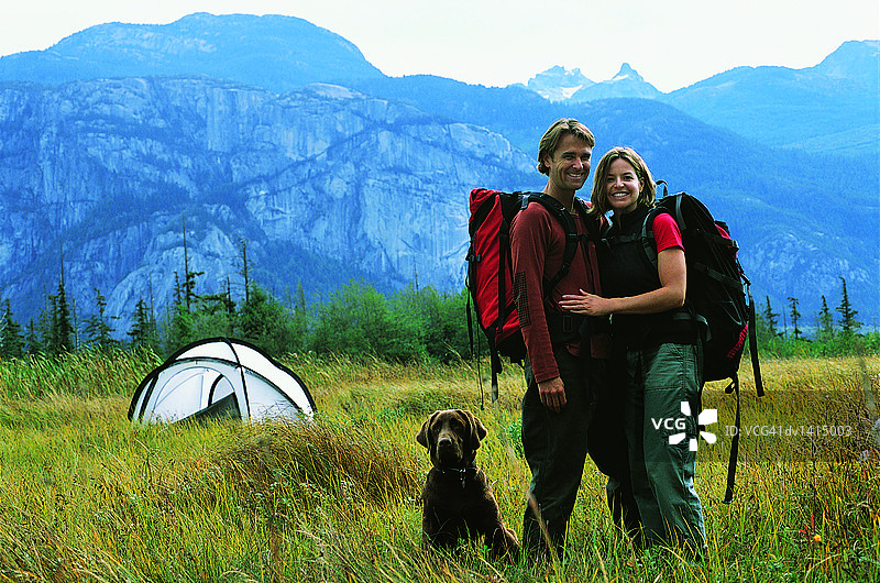 情侣带狗在山边帐篷旁徒步图片素材