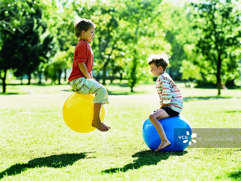 两个男孩在太空跳跳球上弹跳图片素材
