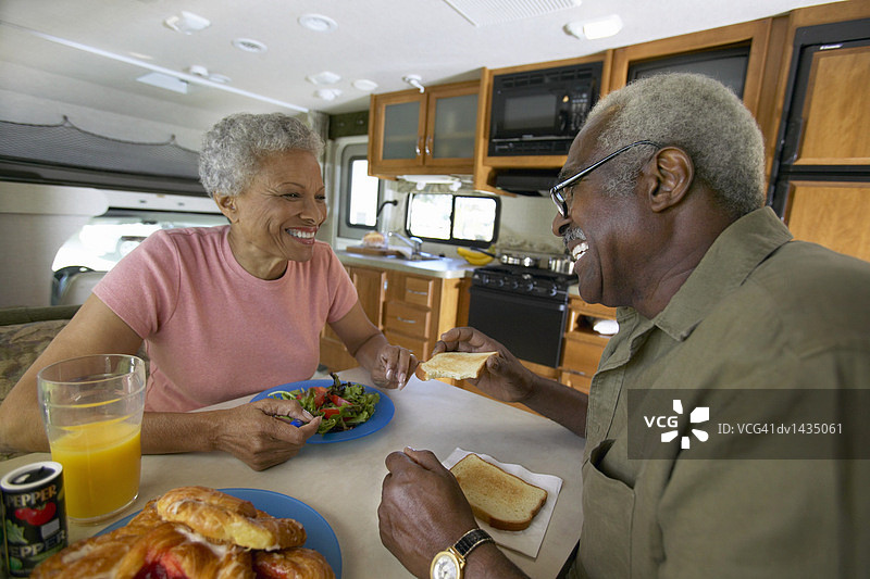 老年夫妇在房车内的桌子旁面对面坐着，享用午餐图片素材