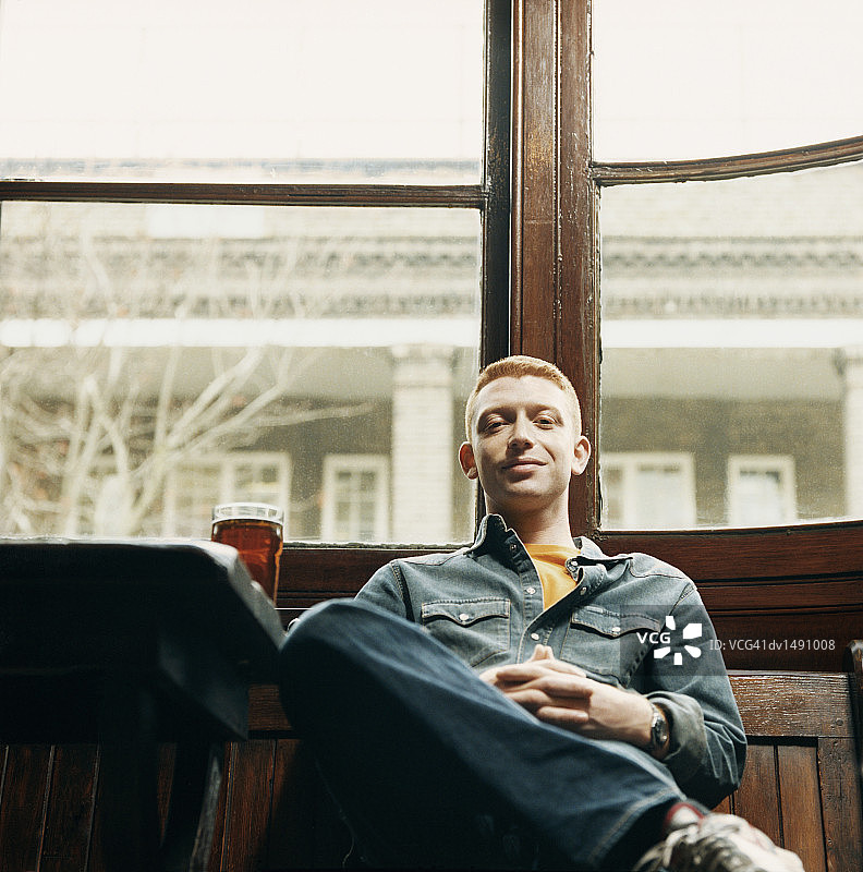 在酒吧里坐在桌旁喝啤酒的男人的低角度视图图片素材