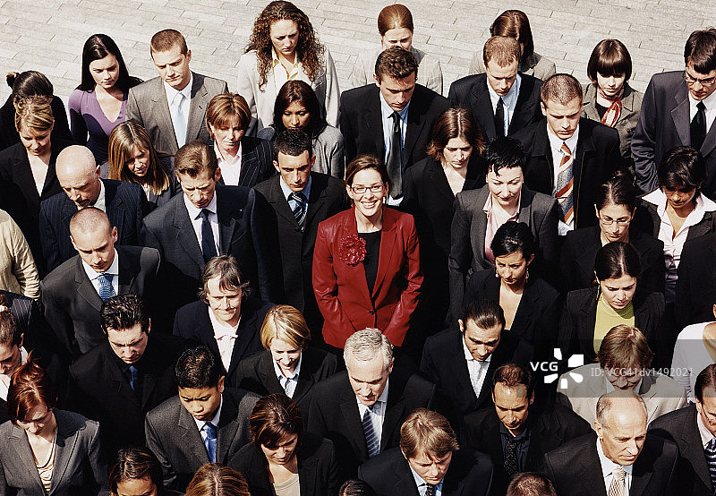 在黑色和灰色西装人群中脱颖而出的红西装女商人图片素材