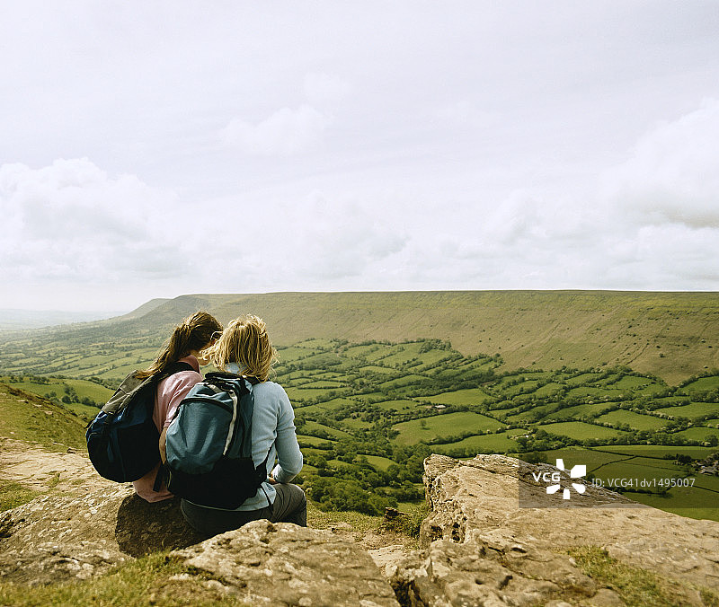 母女在乡村徒步旅行，坐在岩石上图片素材