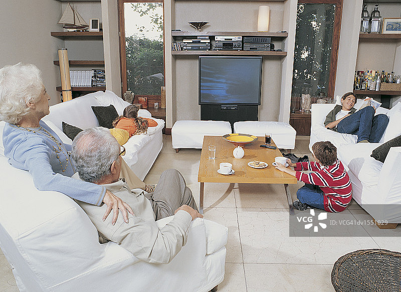 爷爷奶奶和孙子孙女在客厅里看电视图片素材