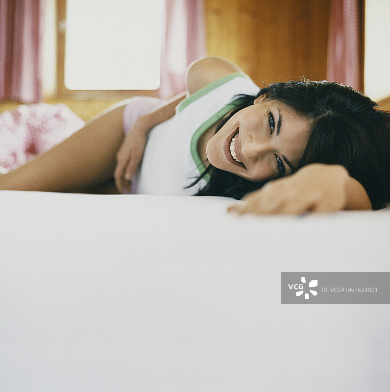 年轻女人躺在床上微笑图片素材