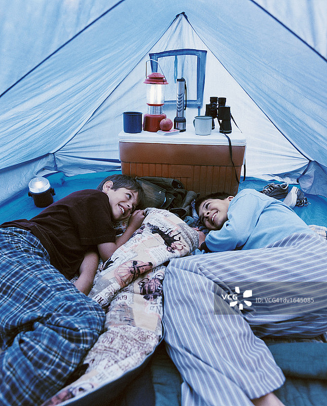 两个穿着睡衣的年轻男孩脸对着脸躺在帐篷里图片素材
