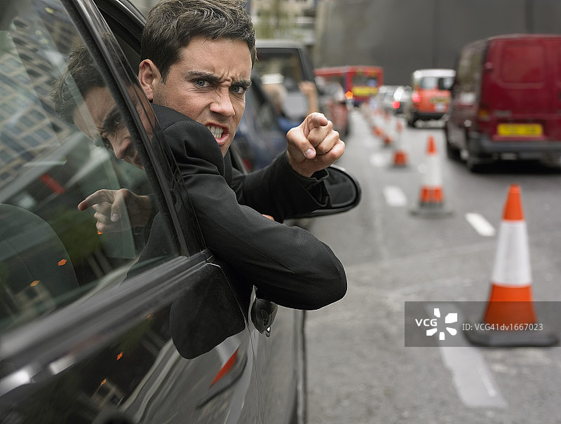 愤怒的男人看着他的汽车窗外图片素材