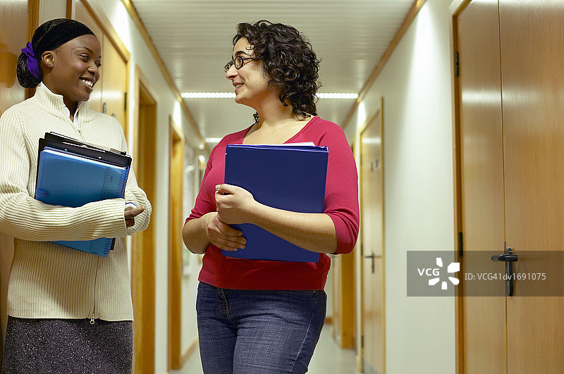 两位中年学生在大学走廊交谈图片素材