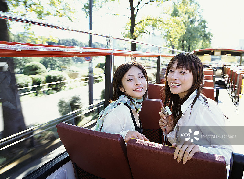 两个女人坐敞篷巴士，一人手持数码相机图片素材