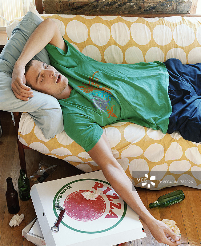 三十多岁的男人躺在公寓的沙发上睡觉图片素材