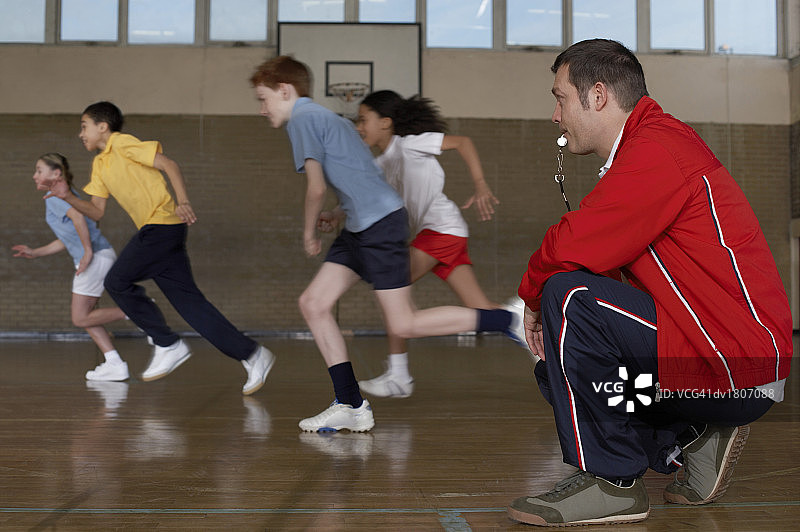 健身教练观看四名学生在学校健身房跑步图片素材