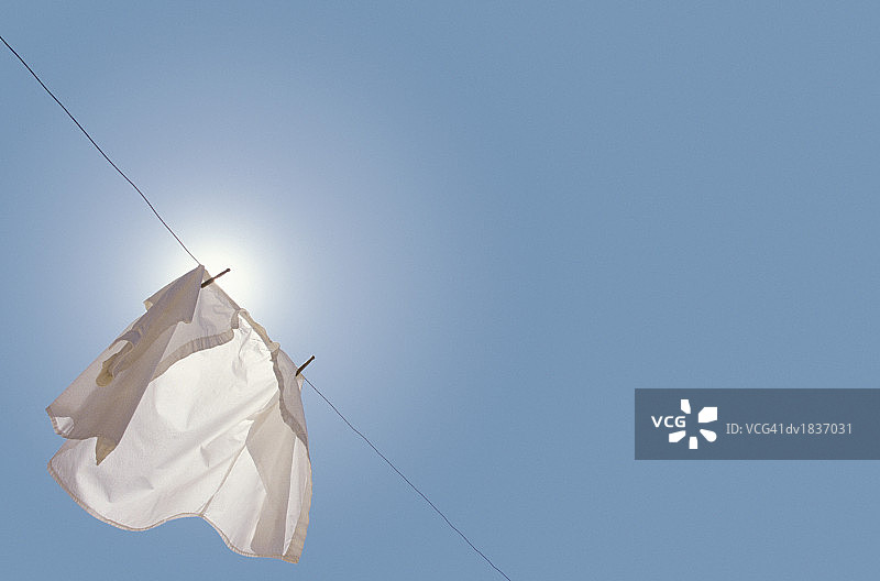 晾衣绳上悬挂的白衬衫，由下往上拍摄图片素材