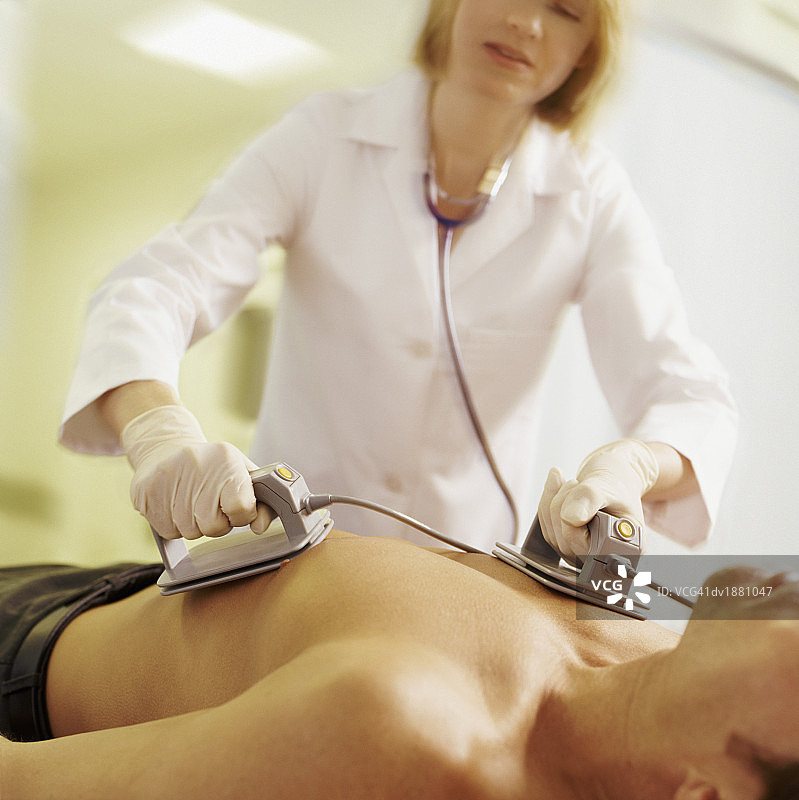 医生用除颤器电击男子胸部图片素材