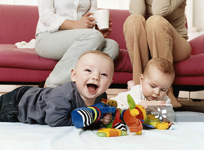 两个婴儿在客厅地板上玩玩具图片素材