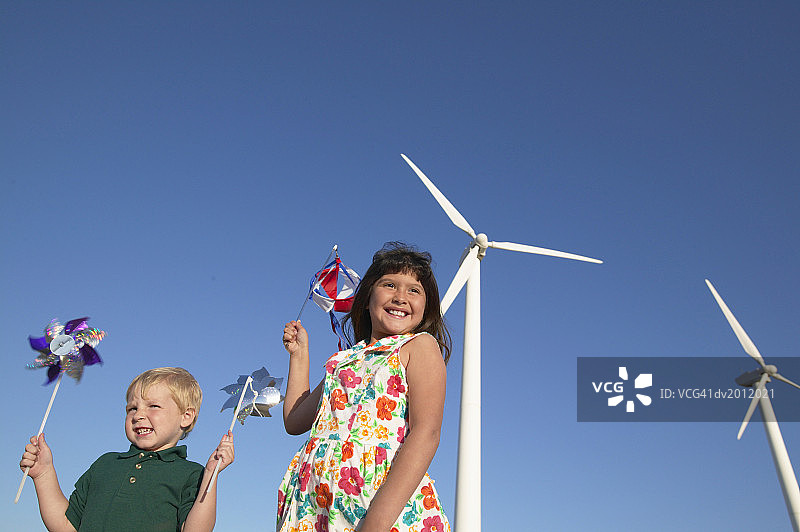 在风力发电场玩风车的两个孩子图片素材