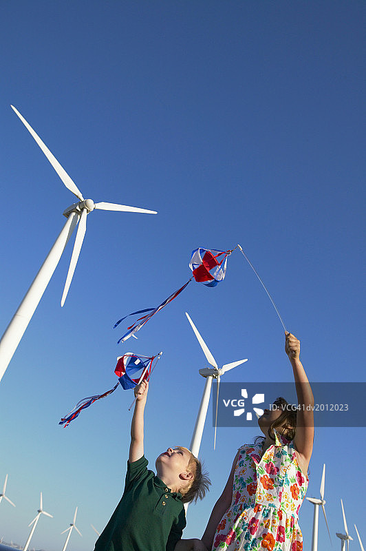 在风力发电场玩风车的两个孩子图片素材