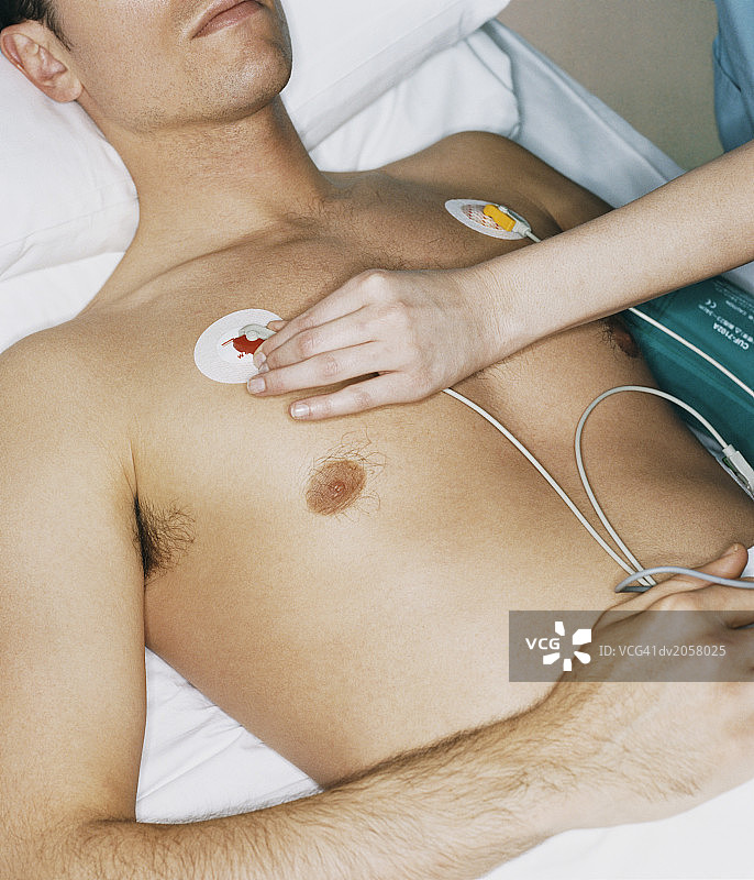 护士调整男性患者胸部的ECG贴片图片素材