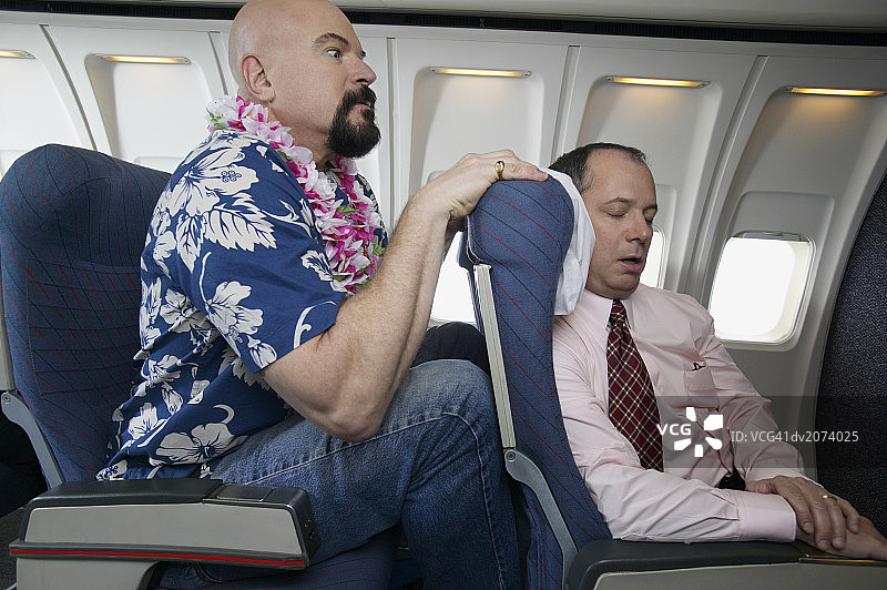 飞机上乘客膝盖顶着熟睡的商人座椅图片素材