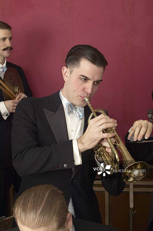 穿着考究的男音乐家在爵士乐队演奏小号图片素材