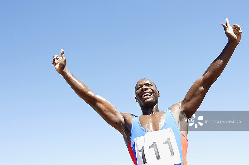 仰视张开双臂庆祝的运动员图片素材
