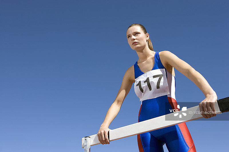 女运动员站在跨栏旁的仰视照片图片素材